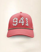 A pink perforated baseball cap showcasing the '941' with a green and white patterned trim along the brim and white 'Palmr' script embroidery on the side, shown against a light beige background.