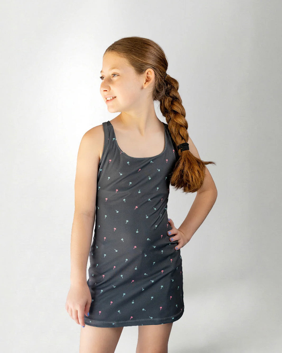 Young girl wearing a dark gray dress with colorful heart patterns on a light gray background