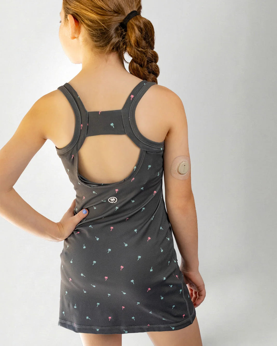Person wearing a dark gray tank top with colorful patterns on a plain background