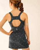 Child wearing Ace Kids Dress with palm print on dark charcoal background, featuring discreet pump-friendly shorts with pockets