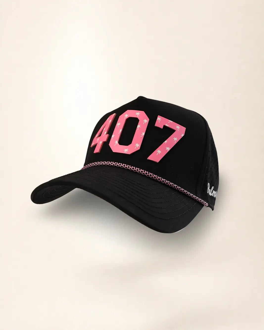 A black trucker-style baseball cap featuring the number '407' in pink with white palms on the front, a pink chain detail along the brim, and a small white script logo on the side, set against a plain light beige background.