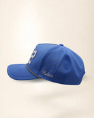 The 772 Signature Hat (Blue), left side view: white Palmr script, perforated side panel, black and white rope, edge of the white 772.
