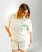 Person wearing a pastel striped outfit with a visible brand logo on a plain background