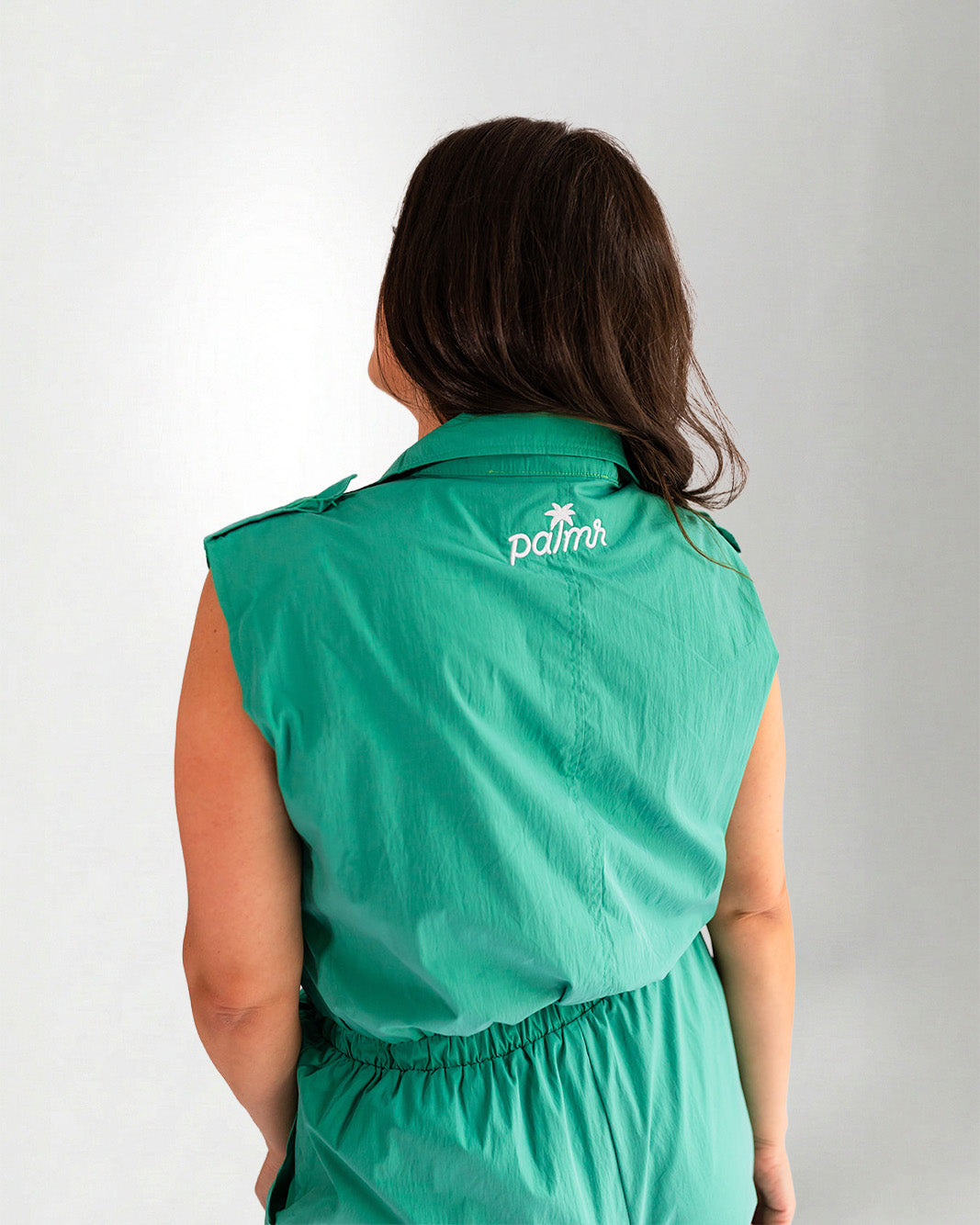 Woman wearing a green jumpsuit on a gray background