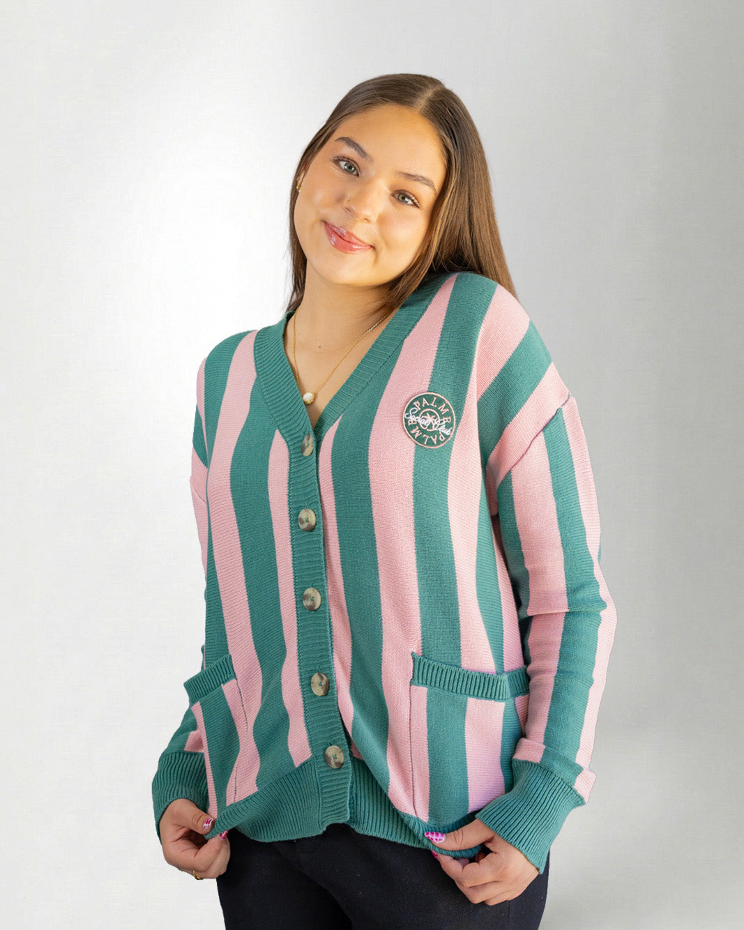 Woman wearing a green and pink striped cardigan on a white background