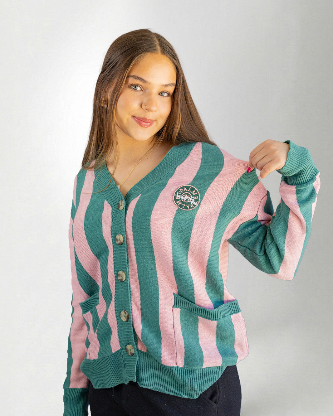 Woman wearing a green and pink striped cardigan on a white background