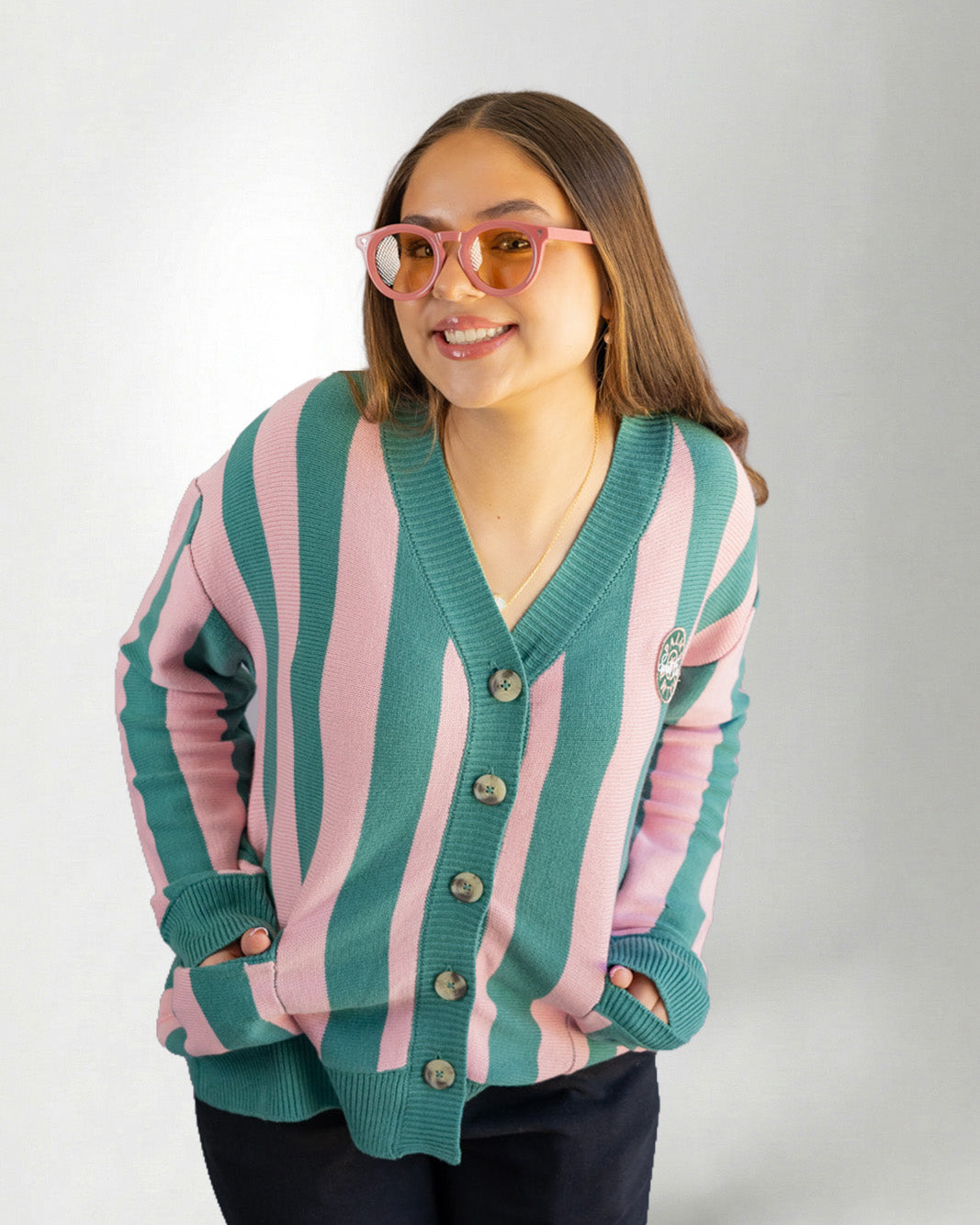 Woman wearing a green and pink striped cardigan on a white background