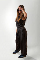 Woman wearing a black outfit with wide-leg pants on a white background