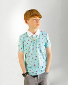 Young boy wearing a light blue polo shirt with colorful patterns on a plain background