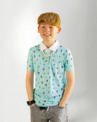 Young boy wearing a light blue polo shirt with colorful patterns on a plain background