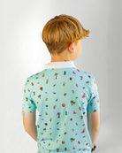 Young boy wearing a light blue polo shirt with colorful patterns on a plain background