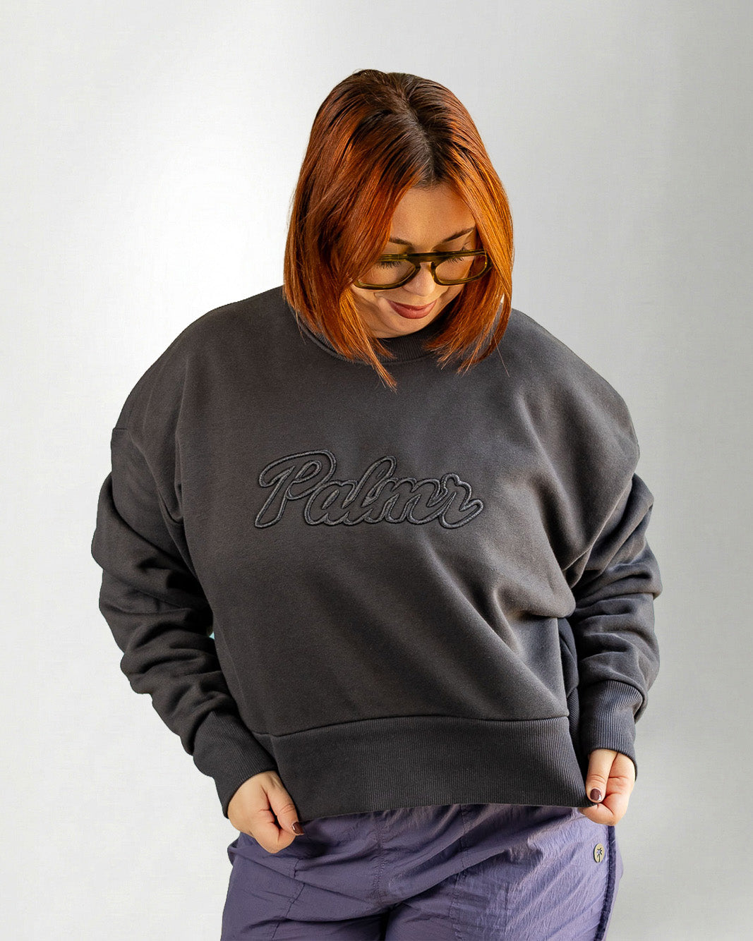 Person wearing a dark gray sweatshirt with 'Palmr' branding on a light gray background