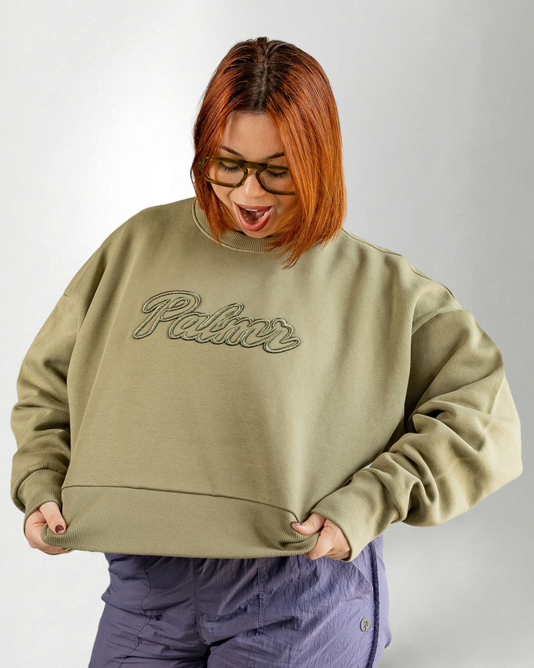 Person wearing a green sweatshirt with 'Palmr' text on a plain background