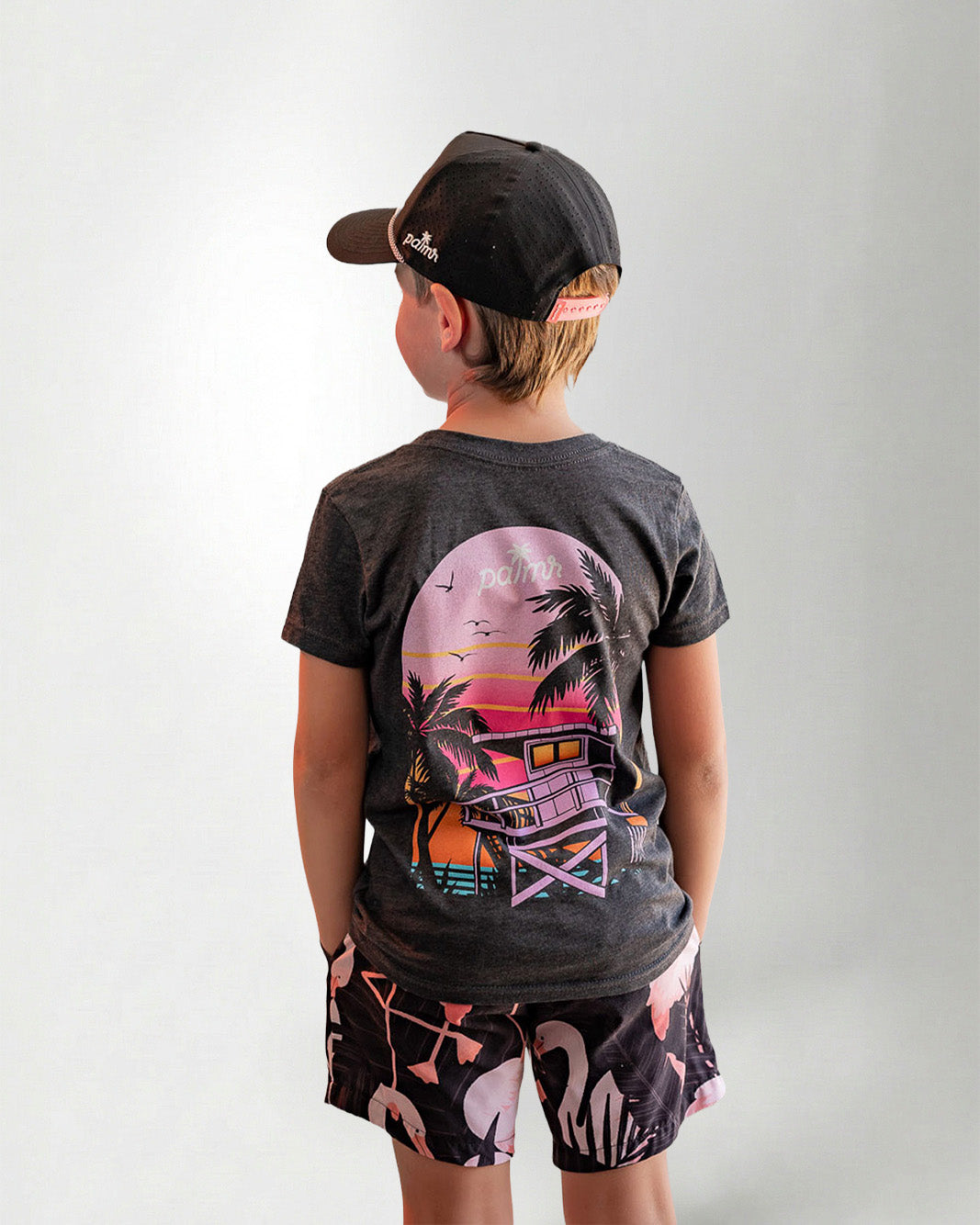 Child wearing a black t-shirt with a colorful graphic design on the back, standing against a plain background.