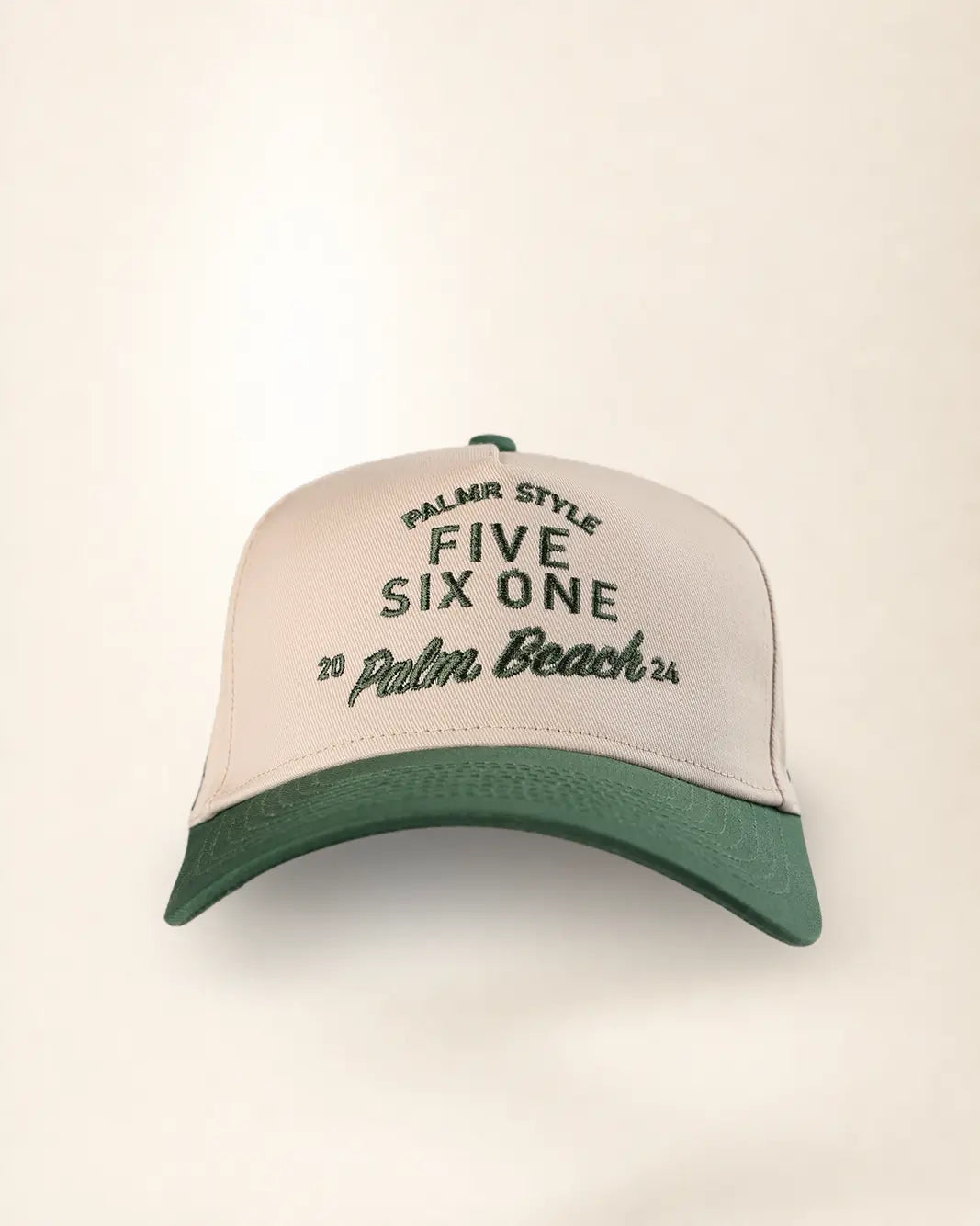 A structured trucker-style baseball cap with a cream-colored front panel and a dark green curved brim. The front panel features embroidered text reading 'PALMR STYLE FIVE SIX ONE 20 Palm Beach 25' in dark green.