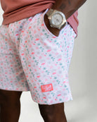 Person wearing pink floral shorts and white sneakers on a plain background