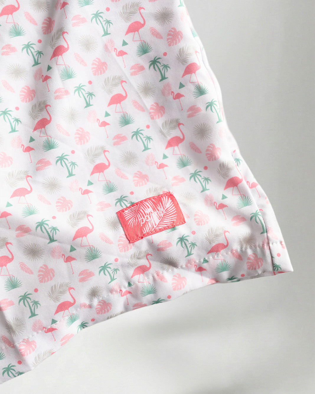 Pink floral shorts and white sneakers on a plain background