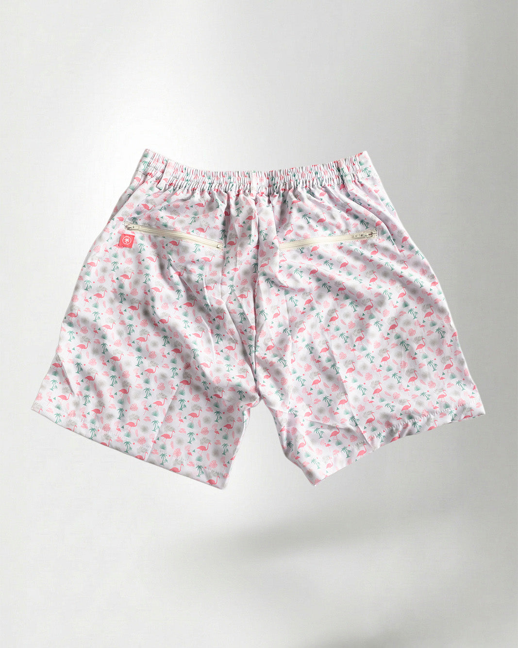 Pink floral shorts and white sneakers on a plain background