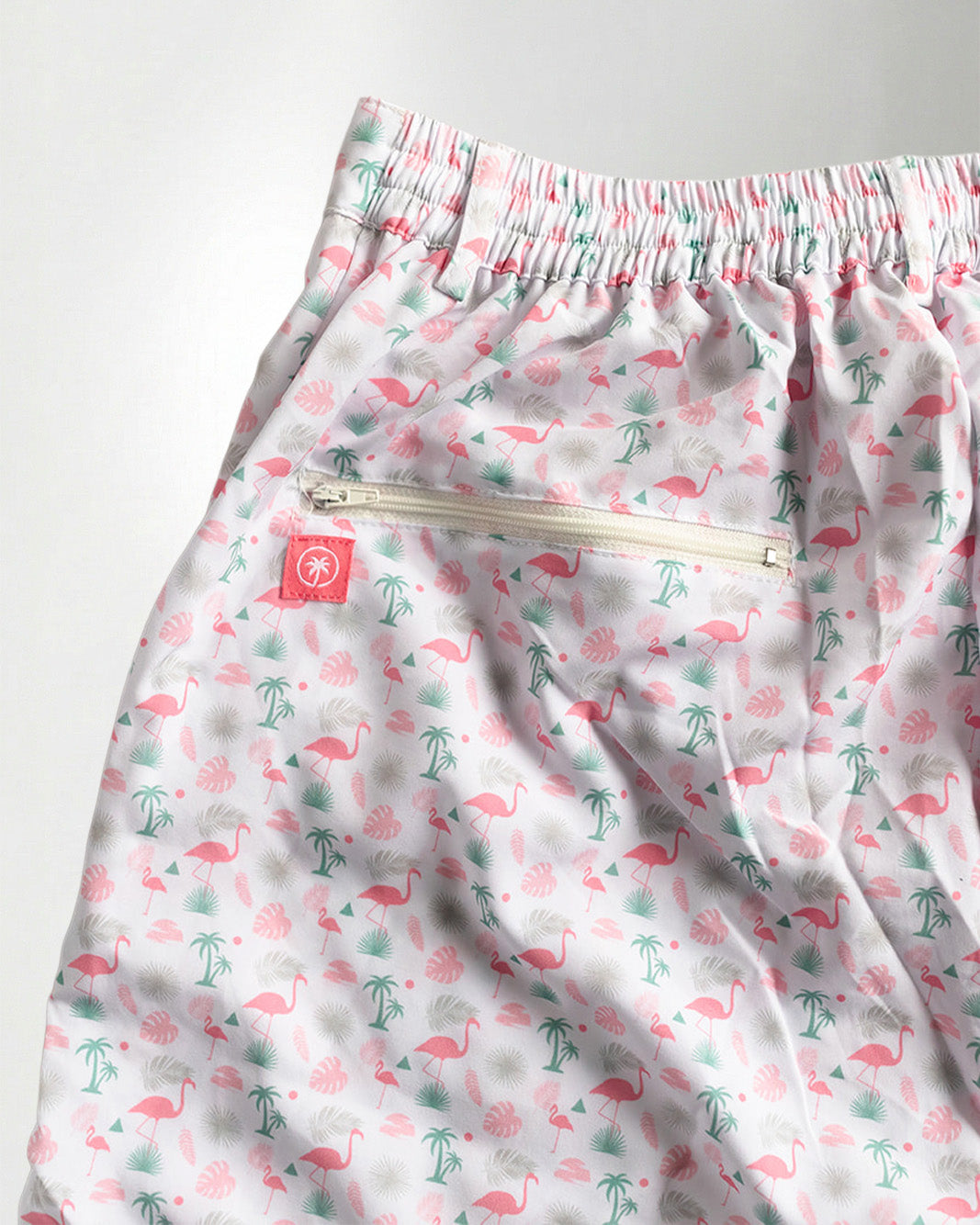 Pink floral shorts and white sneakers on a plain background