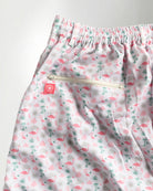 Pink floral shorts and white sneakers on a plain background