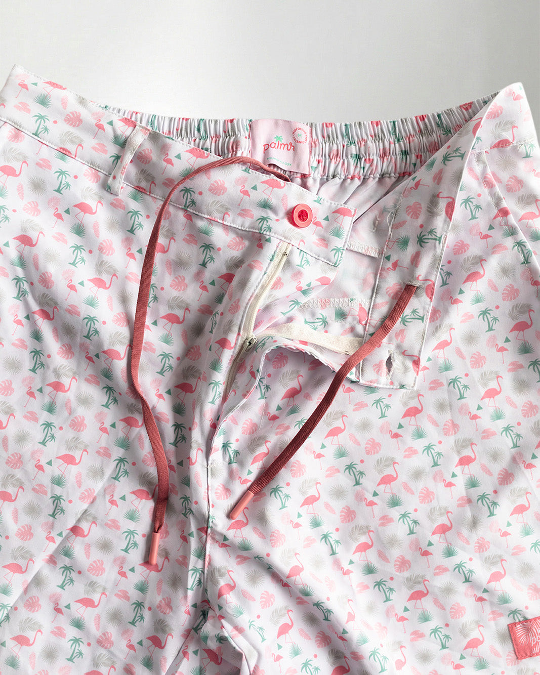 Pink floral shorts and white sneakers on a plain background