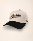 A two-tone baseball cap with a cream-colored front and white back panels, featuring a black curved brim. The front panel has 'Florida' embroidered in black script with a white outline, and the side panel shows 'Palm' embroidered in black script.
