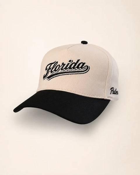 The Florida Heritage Hat (Black): cream and black two-tone with Florida embroidered in black script with white outline, Palmr script on the side.