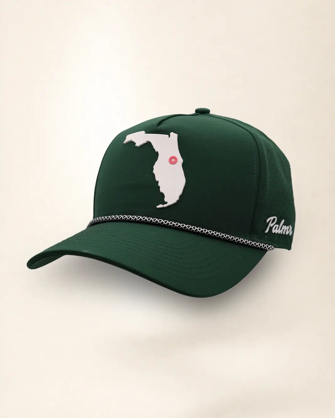 The Florida Signature Hat (Green), three-quarter view: white raised Florida silhouette with a pink dot at Orlando on a dark green rope snapback, braided rope, white Palmr script.