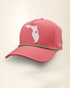 A pink perforated baseball cap showcasing the Florida State with a green and white patterned trim along the brim and white 'Palmr' script embroidery on the side, shown against a light beige background.