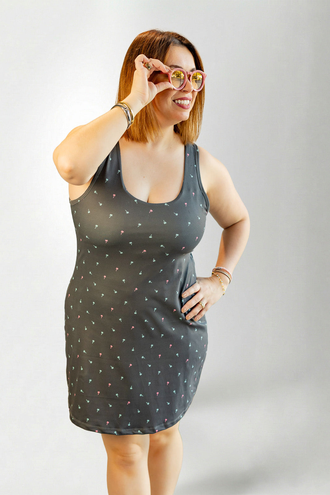 Woman wearing a dark gray tank dress with white polka dots against a plain background