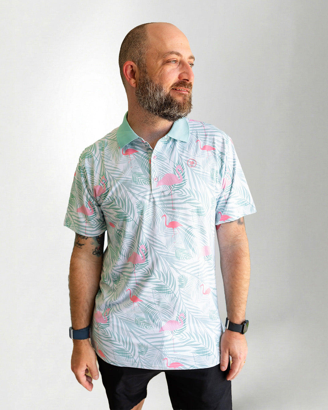 Man wearing a patterned shirt with flamingo design on a plain background