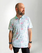 Man wearing a patterned shirt with flamingo design on a plain background