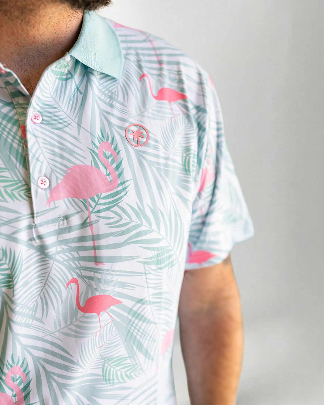 Person wearing a shirt with pink flamingo and palm leaf pattern