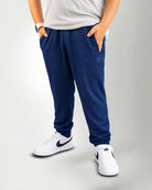 Person wearing navy blue jogger pants and white sneakers on a white background
