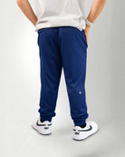 Person wearing navy blue jogger pants and white sneakers on a white background