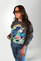 Woman wearing a sweatshirt with a colorful parrot design on a plain background