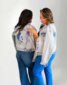 Denim jacket with a colorful parrot design on the back, worn by a person.