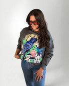 Woman wearing a sweatshirt with a colorful parrot design on a plain background