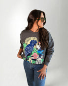 Woman wearing a sweatshirt with a colorful parrot design on a plain background