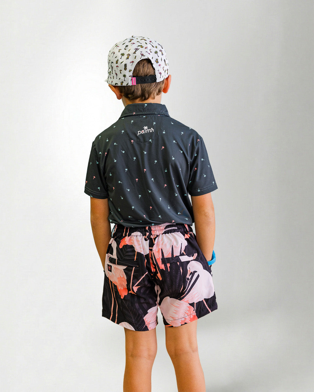 Person wearing a black patterned shirt and shorts with a white bird design on a plain background