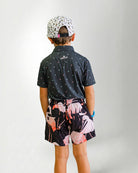 Person wearing a black patterned shirt and shorts with a white bird design on a plain background