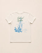 White t-shirt with blue sailboat graphic and text on a beige background
