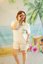 Woman in a white outfit with 'PALACE' logo standing in front of a colorful beach mural.