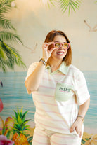 Woman wearing a striped shirt with 'PALM' logo in front of a tropical-themed background