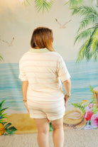 Woman wearing a light-colored outfit standing in front of a tropical-themed wall mural.