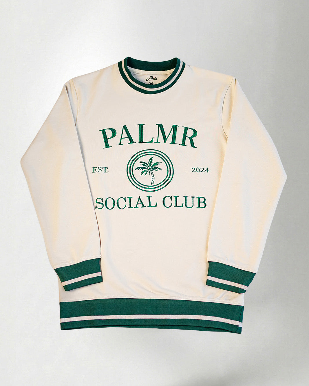 A cream-colored sweatshirt with 'Palmr Social Club' branding on a light gray background