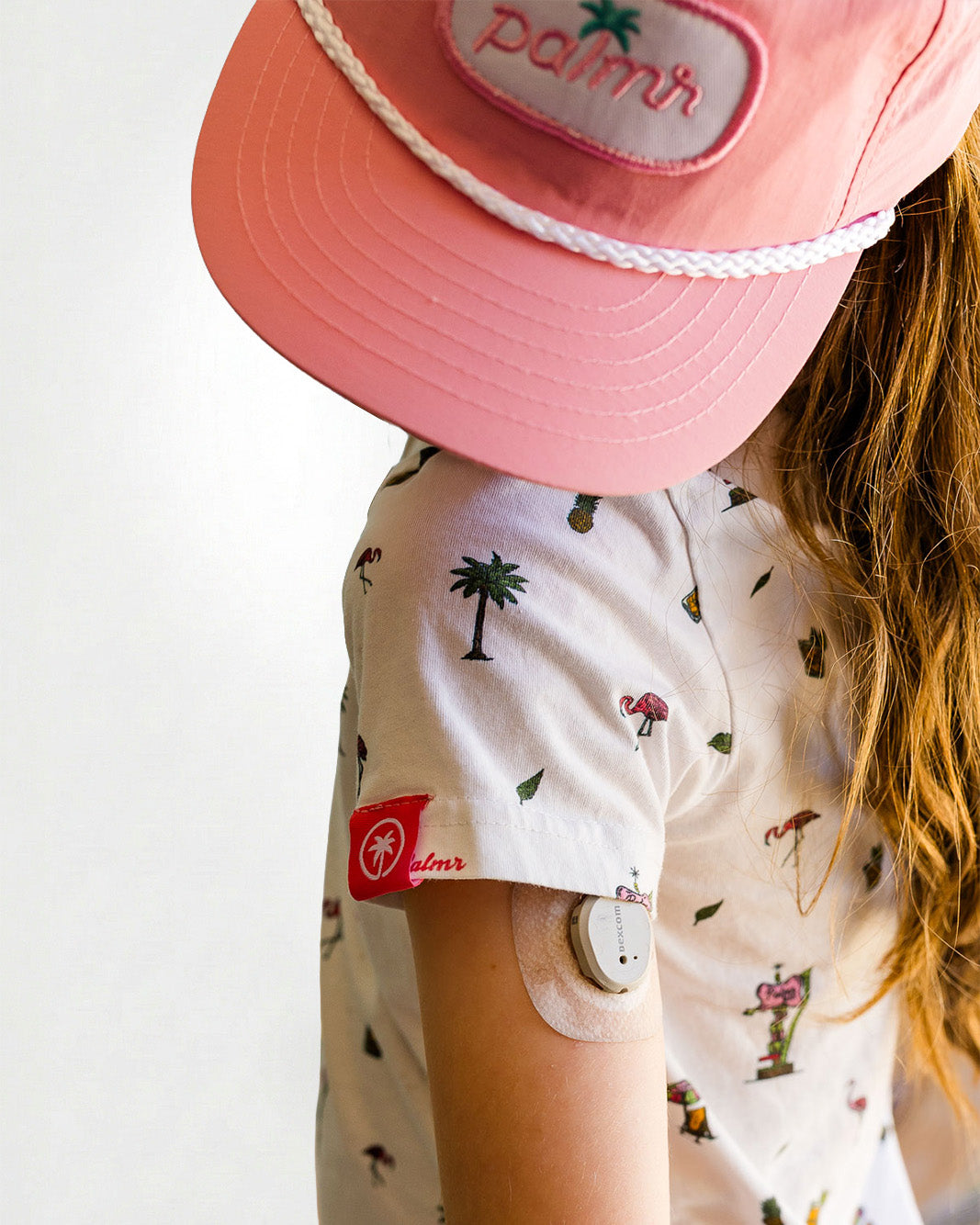 Young girl wearing a patterned shirt and pink pants on a plain background