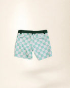 A pair of kid's swim trunks featuring a mint green and white checkered pattern with small palm tree motifs, a dark green elastic waistband, and side pockets, laid flat on a light beige background.