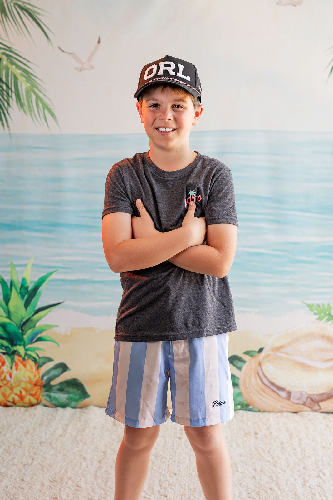Child wearing a cap and t-shirt with a beach-themed background