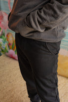 Person wearing a gray hoodie and black pants with a colorful background